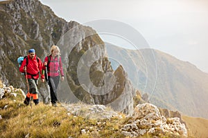 Adventure, travel, tourism, hike and people concept - smiling couple walking with backpacks outdoors