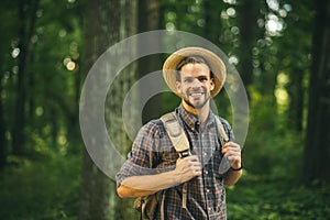 Adventure  travel  tourism  hike and people concept - smiling young man walking with backpack in woods.