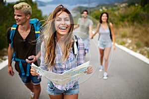 Adventure, travel, tourism and people concept - group of smiling friends with backpacks and map