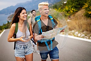 Adventure, travel, tourism and people concept - group of smiling friends with backpacks and map