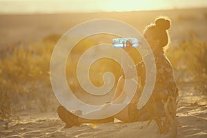 Adventure traveller woman on seacoast at sunset drinking water