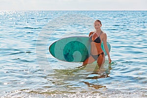 Adventure trip concept. Fit girl in swimsuit with surfboard. Sunny day on sandy seashore. Summer time, surf sport idea.