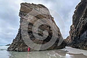 adventure woman explorer walking in the sea between cliffs Playa de las Catedrales Galicia Spain