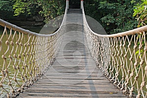 Adventure wooden rope suspension bridge crossing river