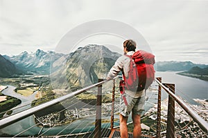 Adventurer man with red backpack enjoying mountains scenery