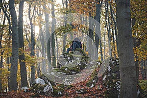 Adventurer sitting on a rock in autumn forest in Strazovske mountains, Slovakia. A man with a smile rests after a hard hike