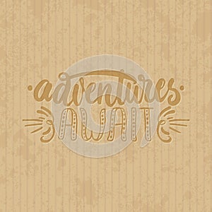 Adventures await - hand drawn lettering phrase isolated on the cardboard grunge background. Fun brush ink inscription