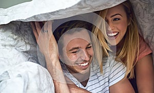 Adventures under the duvet. Shot of a happy young couple having fun under a duvet in bed.
