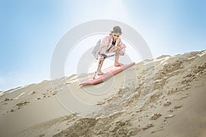An adventuresome Little Girl boarding down the Sand Dunes