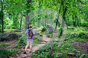 Adventuress or traveler woman go hiking on trail in forest