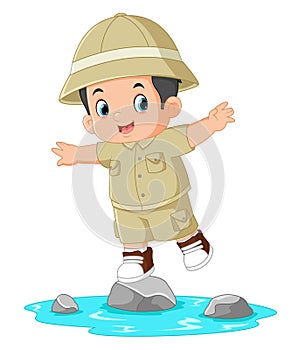 an adventurous boy jumps between the rocks in the river