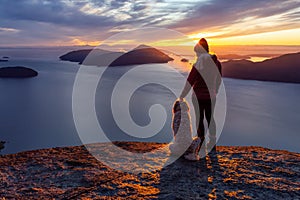 Adventurous Girl Hiking on top of a Mountain with a dog