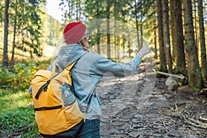 Adventurous girl with a yellow backpack and in sportswear navigating looking for direction in the beautiful mountains of