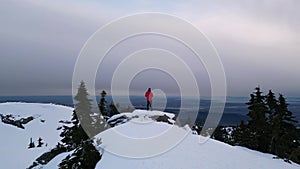 Adventurous Man Hiker on Snowy Mountain with Trees. Cloudy Sunset Sky. British Columbia, Canada
