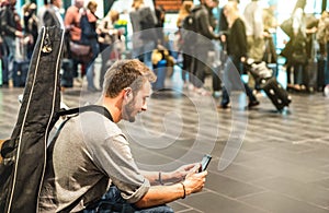 Young man at international airport using mobile smart phone on terminal gate