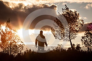 Adventurous man observing a lovely sunset in nature, alone, stan