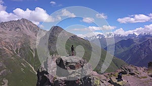 Adventurous man is standing on top of the mountain and enjoying the breathtaking view. Clip. Aerial view of beautiful