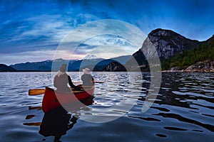 Adventurous people on a canoe with Mountains Behind