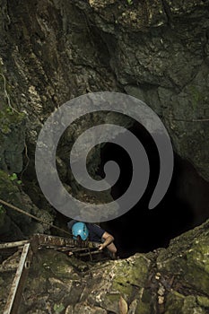 Adventurous woman descending into a deep cavern by metal stairs secured by a harness Costa Rica in Guanacaste