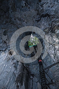 Adventurous woman descending inside a deep cavern by metal stairs secured by a harness Costa Rica in Guanacaste