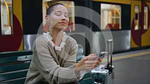 Adventurous woman waiting train looking on smartphone close up. Short hair girl