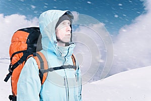 Adventurous young man with backpack standing on mountain top view and looking out. Mountaineering, extreme sport.