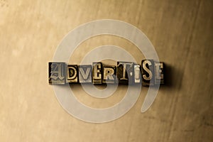 ADVERTISE - close-up of grungy vintage typeset word on metal backdrop