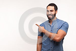 Advertise here! Positive bearded man pointing finger away paying your attention at empty space for advertisement, looking at