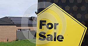 The advertisement sign of \'for sale\' with a blurry background of vacant land and modern residential houses.