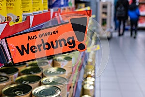 Advertisement in a supermarket with a sign and the text \'From our advertising\' in German