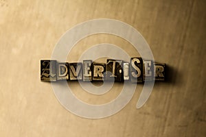 ADVERTISER - close-up of grungy vintage typeset word on metal backdrop