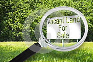 Advertising billboard immersed in a rural scene with Vacant Land for Sale written on it - concept image seen through a magnifying