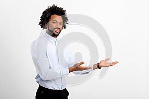 Advertising concept. Handsome curly young man in white shirt presenting, pointing hands aside, advertising new product