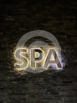 Advertising sign spa area on a black brick wall