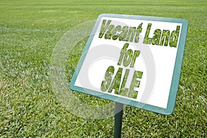 Advertising signboard with Vacant Land for Sale written on it against a green meadow - concept image