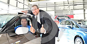 Advice in the car dealership - seller and young man selling a new car