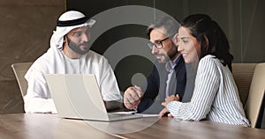 Advisor in muslim robe showing presentation on laptop to clients