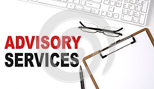 ADVISORY SERVICES text written on the white background with keyboard, paper sheet and pen