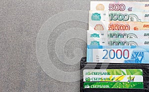 Russian banknotes in denominations of 1000, 2000 and 5000 rubles and credit cards Sberbank in a black leather purse close-up, on a