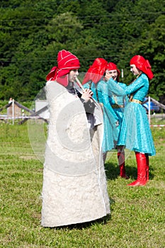 Adyghe boy in Circassian national dress playing the flute in the background laughing girl, selective focus