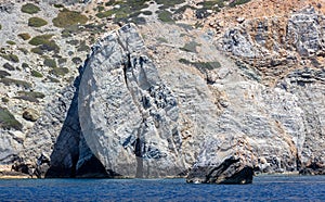 Aegean Sea. Rocky coast, cliff and cave, rippled ocean. Cyclades Greece. Seascape near Nios island photo