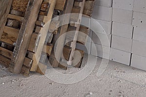 Aerated concrete blocks on the floor with wooden pallets in a building under construction, sunlight on the right