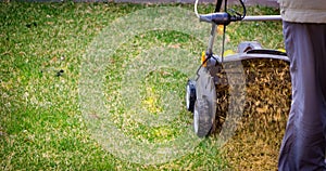 Aeration of the lawn in the garden. Yellow aerator on green grass photo
