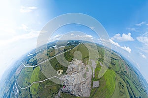 Aerial 360 panoramic of opencast mining quarry minerals with many machinery tractors and trucks surrounded by green fields