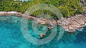 Aerial 4K fly exotic tropical jungle island with coral reef and blue ocean water at Mahe island, Seychelles