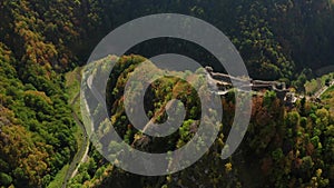 Aerial 4K view of Poenari Fortress at the bottom of Fagaras Mountains surrounded by forests in autumn colors