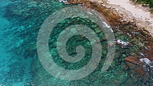 Aerial 4K view of remote secluded tropical beach with old coral reef in transparent water surface. Mahe island