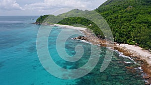 Aerial 4K view of tropical island coastline with coral reef and blue lagoon at Mahe island, Seychelles