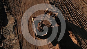 Aerial above excavator loading a dump truck with dirt on a construction site