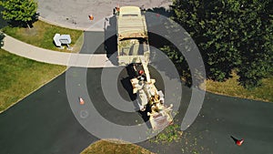 Aerial above view of Maintenance worker loading cut tree branches into the wood chipper machine for shredding